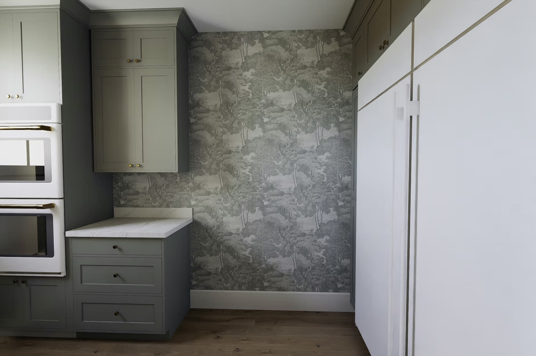 Pantry with sage green cabinetry and wallpaper